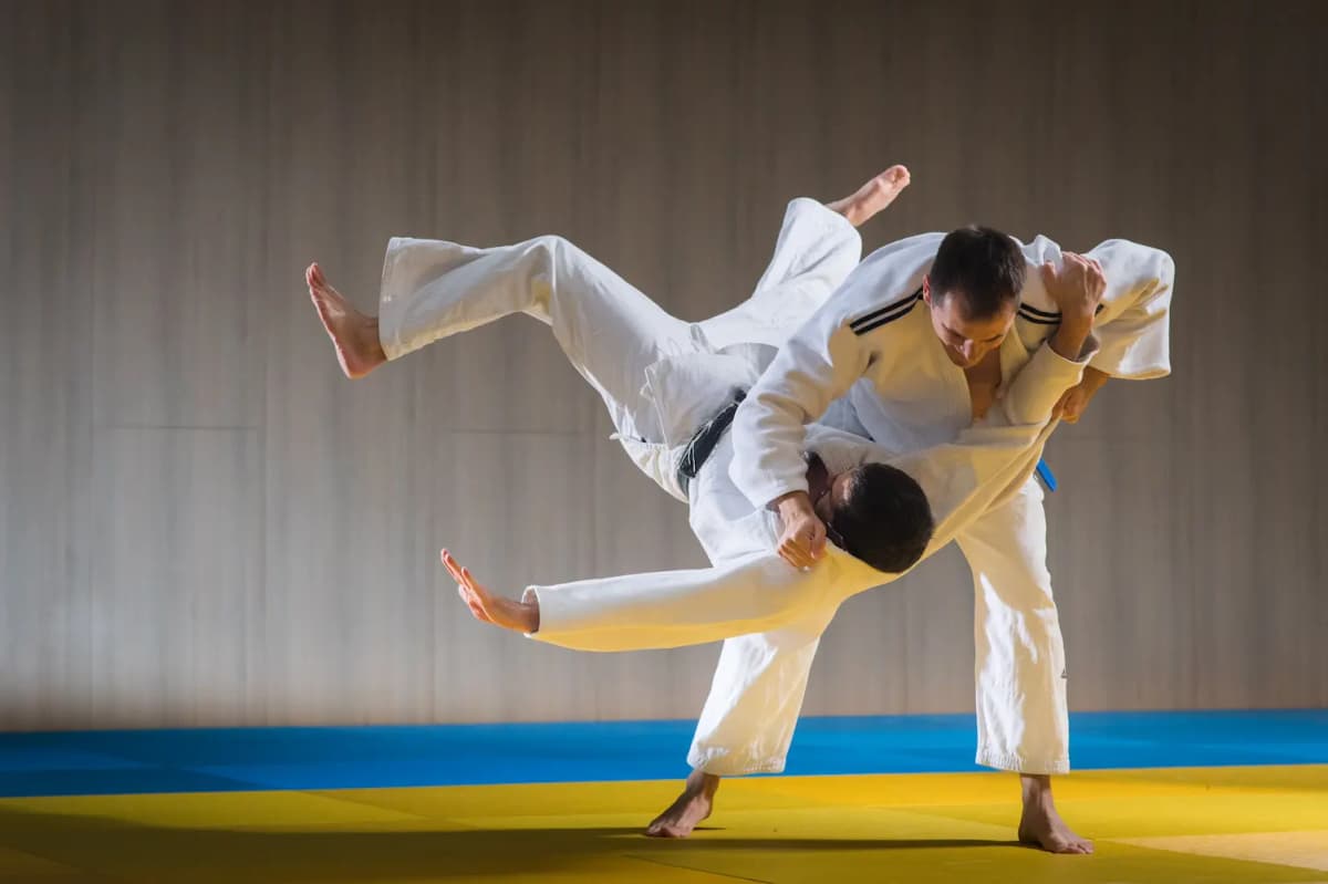 Twee sporters in een witte gi tijdens een worp op de mat